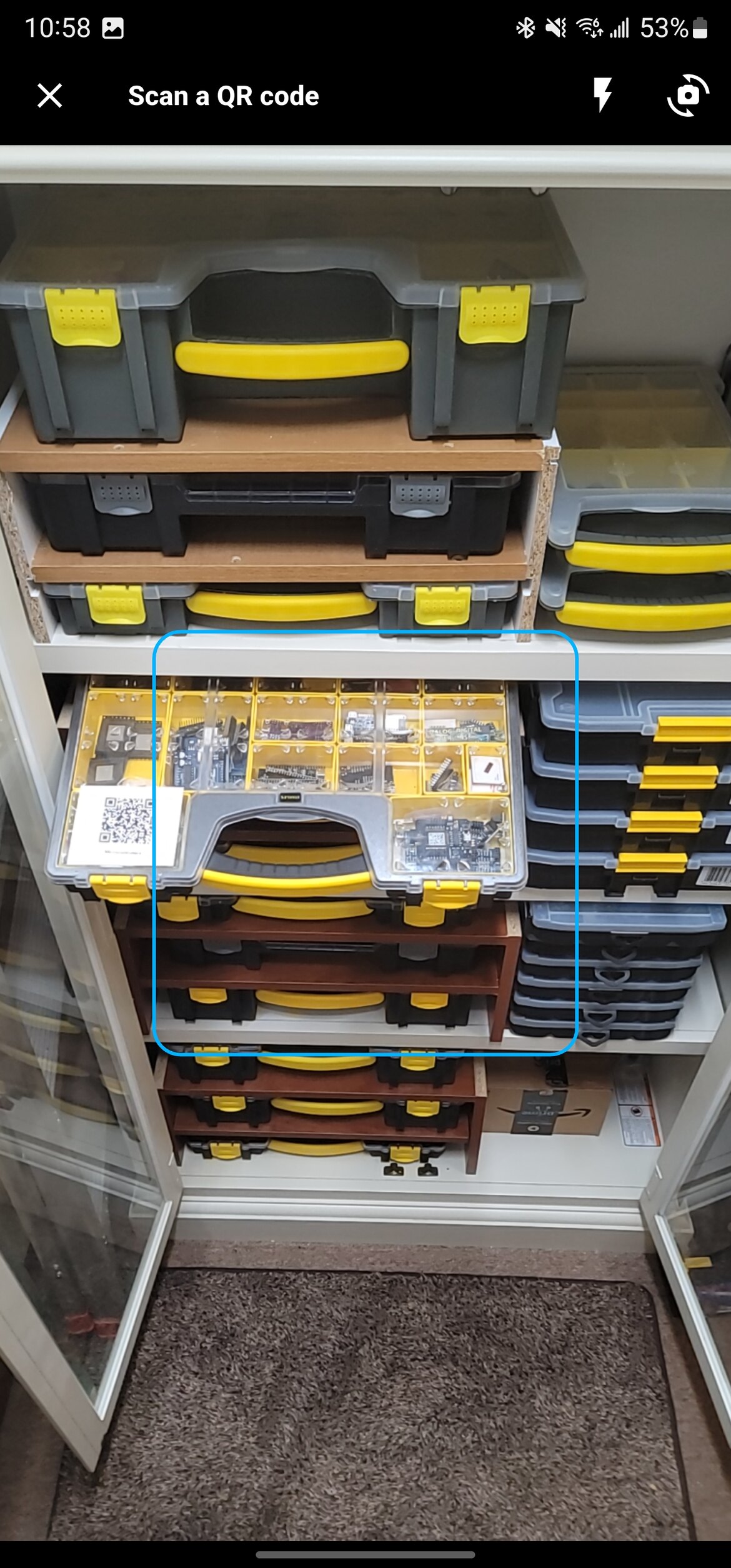 The in-app scanner pointed at a cabinet of small-parts organisers, one of them wearing a printed Lyztin label